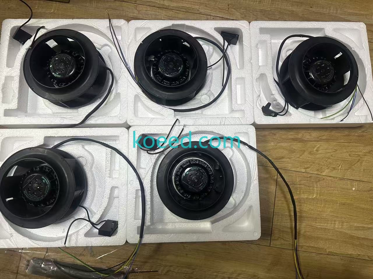 Five black fan assemblies with cables and loose leads in separate white foam trays on a wooden surface; photographed count agrees with the historical five-item note.